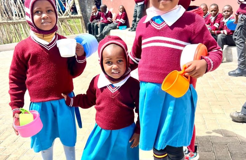 Three young pupils holding hands outside the school