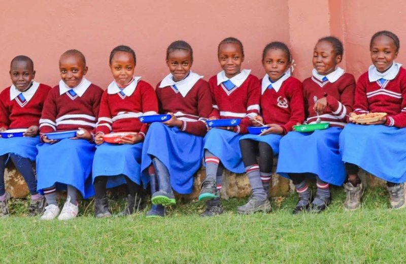 Girls in red and blue uniform seated in a row
